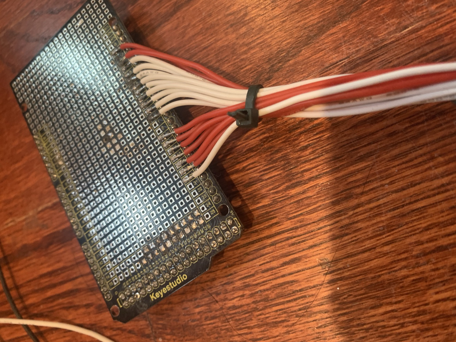 Prototyping shield with a soldered red and white wire harness leaving through a cable tie