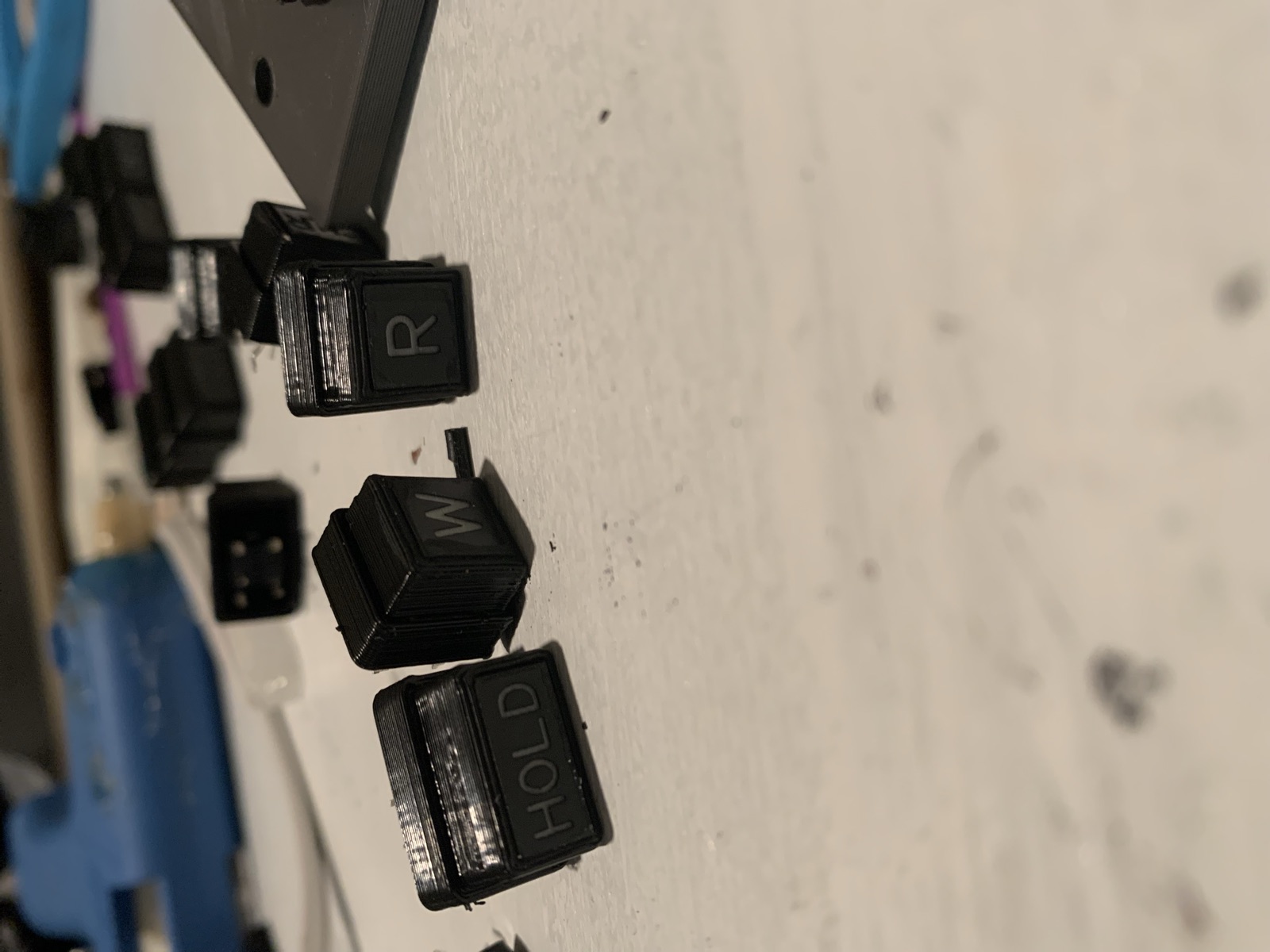 Individual black FMC key caps including HOLD, W and R on the workbench
