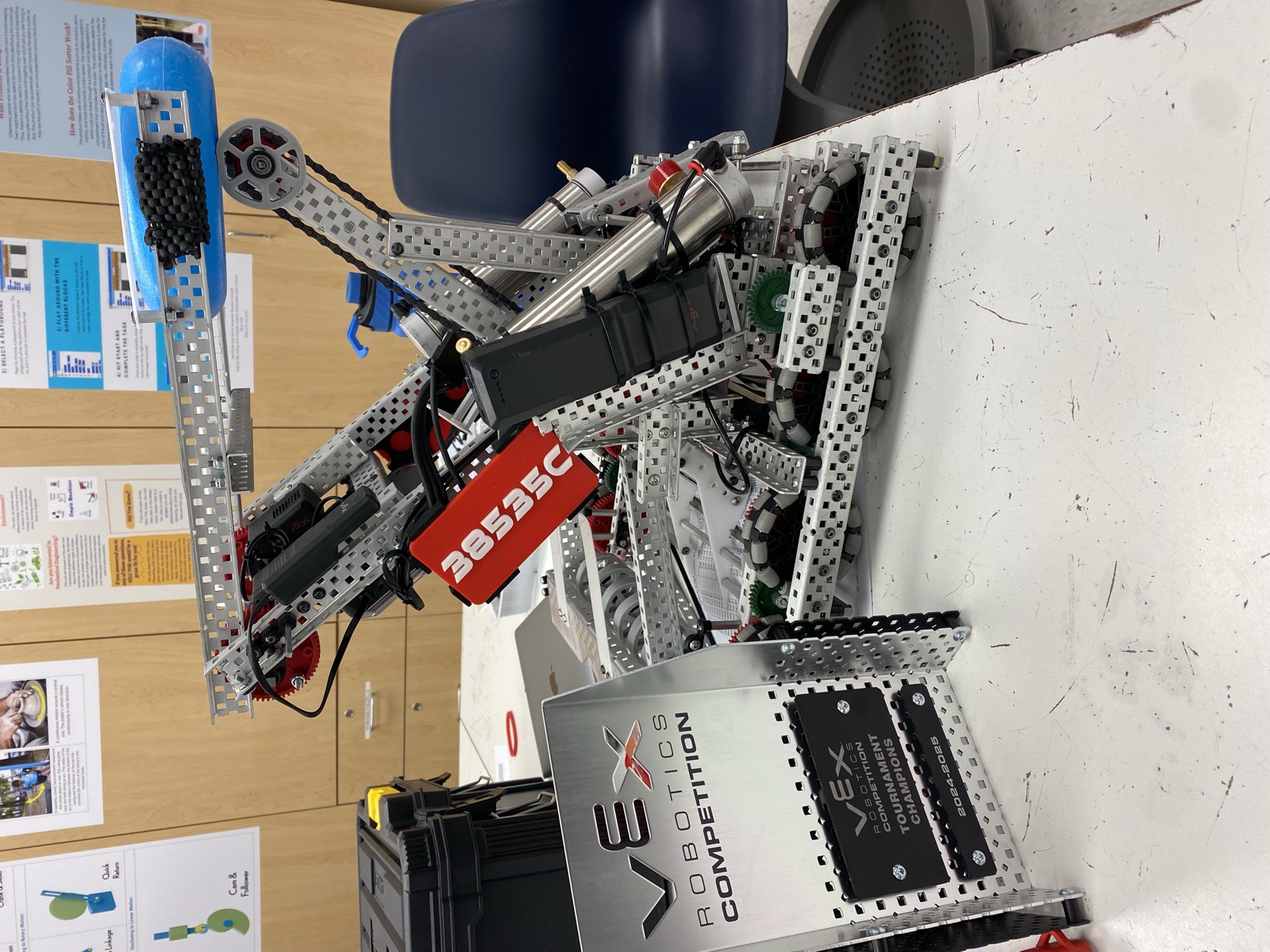 The robot set up in the workshop next to the VEX tournament champions award and its air tank