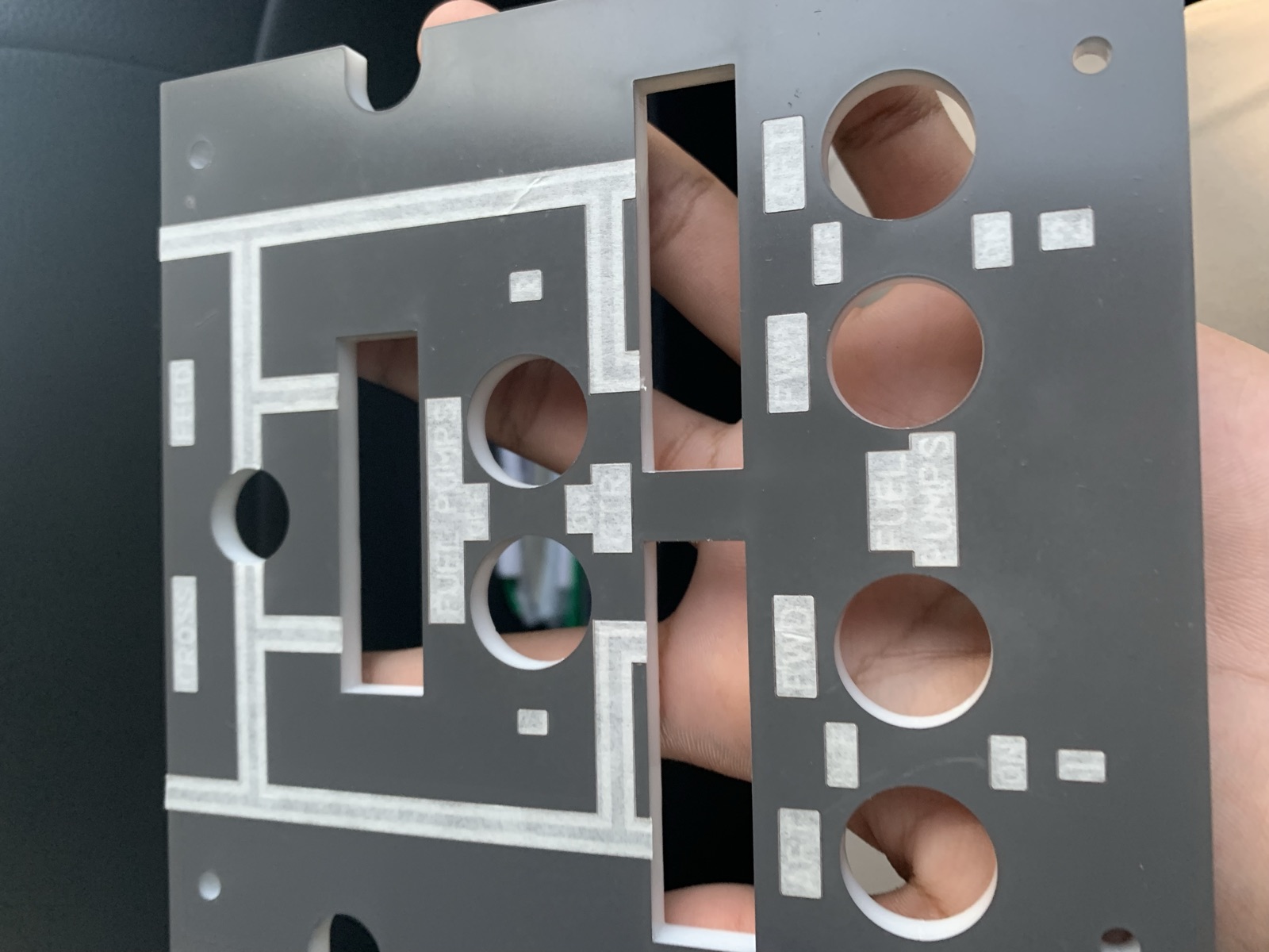 Close view of a white fuel pump panel with engraved CROSS FEED and FUEL PUMPS labels and switch holes