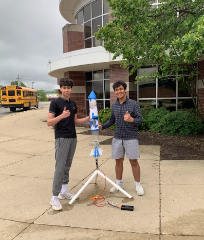 Two of us standing beside the finished rocket on its launch stand outside the school