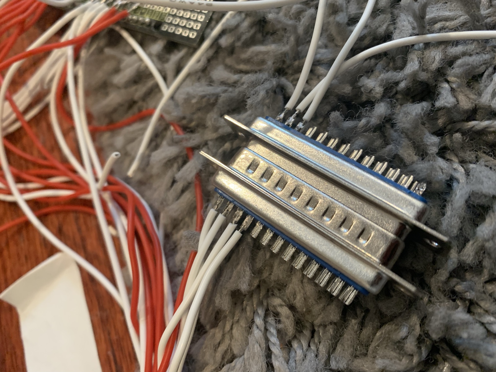 Two metal shielded multi pin connectors with red, white, and gray wires soldered to their pins